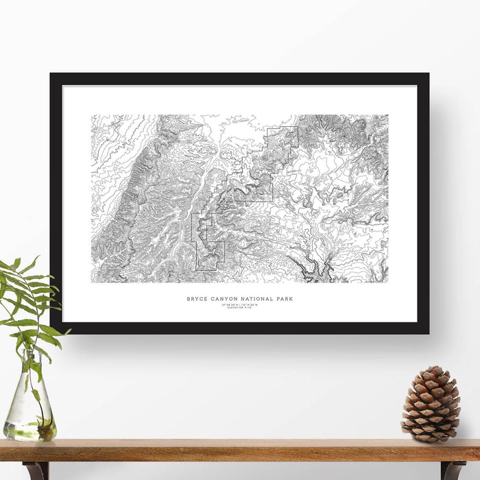 Map wall decor in a black frame. Contour lines of Bryce Canyon National Park are drawn on a white background. Text  below the map can be customized to create custom adventure art.