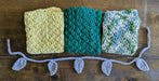 Photograph of the three kitchen towels folded up and placed next to each other, alongside the tie.
