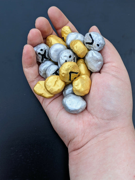 Photograph of the gold and silver stones in the creator's hand, for scale.