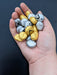 Photograph of the gold and silver stones in the creator's hand, for scale.
