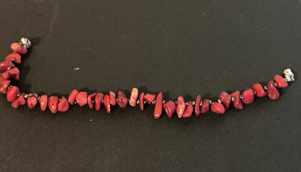 Beaded bracelet consisting of alternating red coral chip beads and metallic multicolored glass seed beads