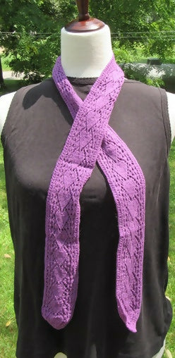 a narrow purple long scarf with an arrow-like motif on a dress form