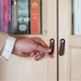 Woman's hand reaching for small dark brown leather tab handles on an IKEA BILLY bookcase door