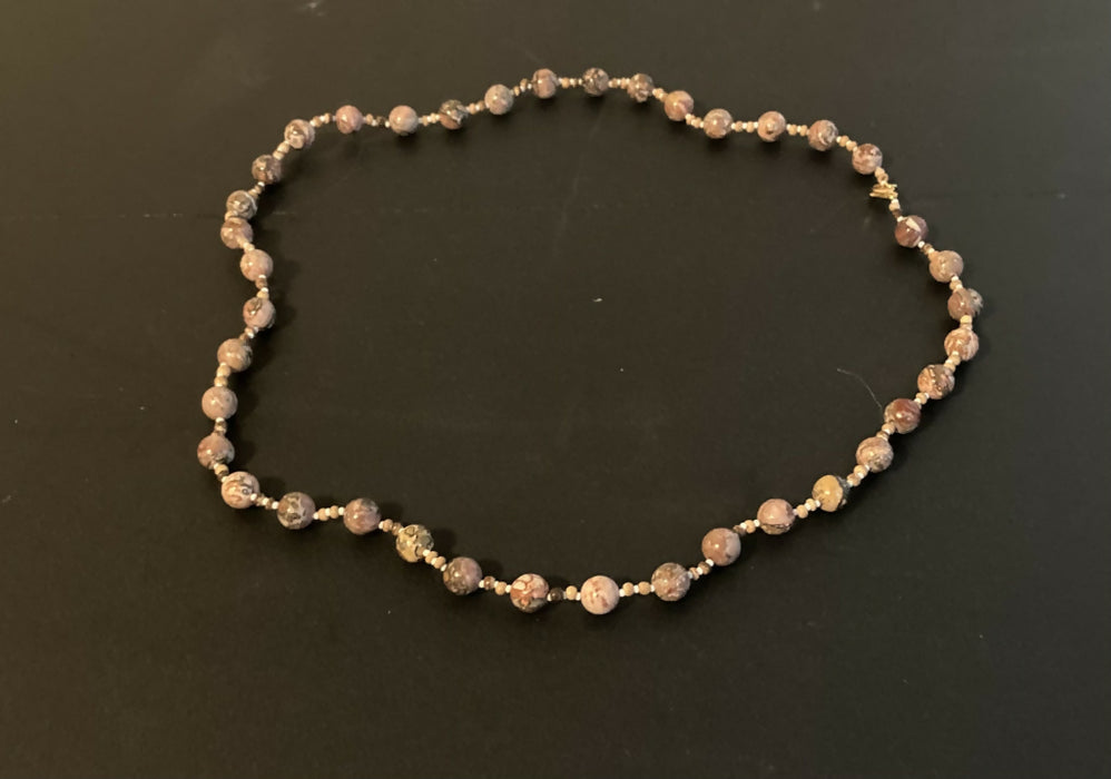 Necklace made of spherical speckled stone beads, small round wooden beads, and white glass seed beads, in an alternating pattern.