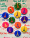 A white board has 12 round, shiny magnets in bright colors. Each has the same line drawing of the Eiffel Tower.