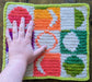 Photograph of the rainbow tarot cloth with the creator's hand on it for scale.