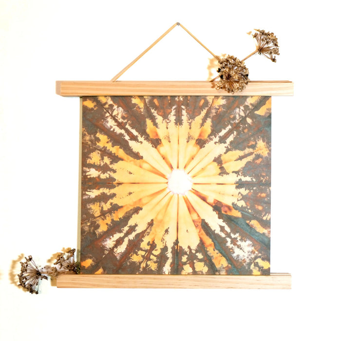 red tea with chrysanthemum print in a poster frame made of two bars of wood running along the top and bottom of the print, with dried chive blossoms sticking out of the bars