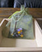 Photograph of the nonbinary stitch markers in a green tulle bag, resting in a square wooden tray.