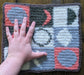 Photograph of the green, pink, and grey tarot cloth with the creator's hand on it for scale.