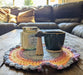Photograph of a candle, a small ceramic cup, and a ceramic mushroom on the altar cloth.