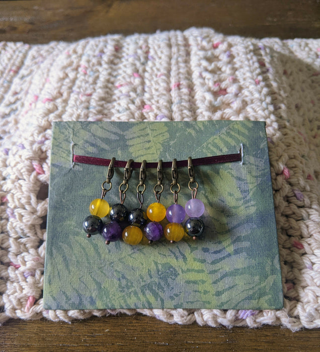 Photograph of a set of six beaded stitch markers inspired by the nonbinary flag.