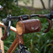 Dark brown leather bicycle barrel bag on handlebars with wood end pieces