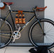 Honey leather and bamboo six-pack held on the top tube of a black bicycle with a 6-pack beer carrier, the 6-pack frame cinch on a custom branded bike for an Australian brewery