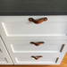 Customer photo looking down a series of white kitchen drawers from standing at the countertop. Each drawer has a small Hawthorne leather handle installed flat with two sets of hardware. 