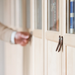 Woman's hand reaching for small dark brown leather tab handles on an IKEA BILLY bookcase door