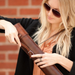 Woman closing leather blueprint case by sliding buckle into steel hardware while over the shoulder
