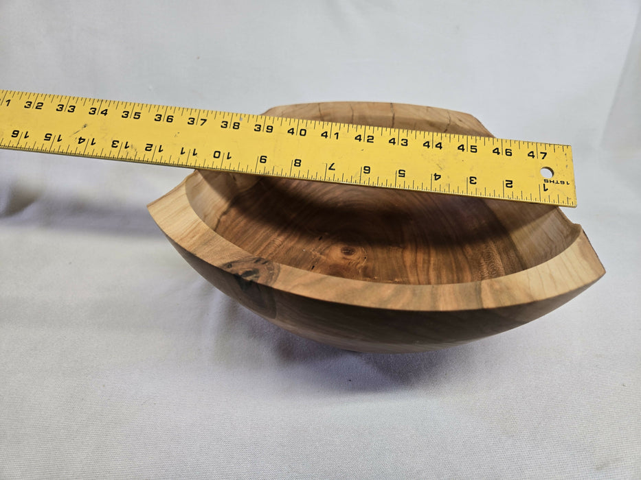 A picture of a wooden cherry bowl with a ruler on top measuring 11 inches