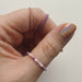 A woman's hand wearing three pink, purple and white beaded rings.
