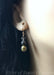 Elegant 3-ball dangle earrings, shown on a mannequin. Colors are translucent gray, grayish black, and gold.